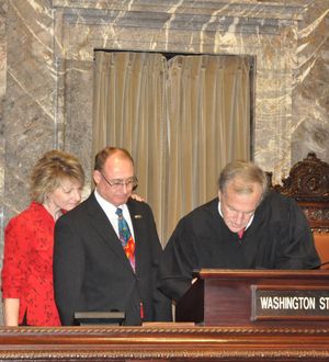 Newly sworn-in Sen. Jeff Baxter and his wife Diane watch as Supreme Court Justice Jim Johnson signs the oath of office Baxter took Monday morning as the new senator from Spokane's 4th Legislative District.  (Jim Camden/The Spokesman-Review)