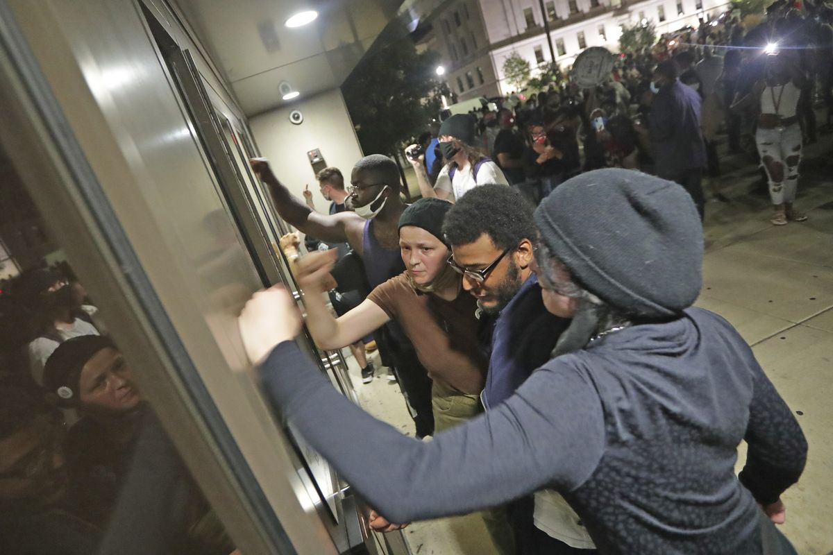 People pound on the Kenosha Police Department door Sunday in Kenosha, Wis.  (Mike De Sisti)