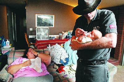 
At left: Walter Scott Edwards II, right, holds his newborn son Walter Scott Edwards III as his fiancée, April Branum, who gave birth to the full-term baby just two days after learning she was pregnant, rests on the couch. What the couple didn't need or expect was the deluge of nasty – and anonymous – public comments posted on the Web site of the Orange County Register, which reported their story. 
 (The Spokesman-Review)