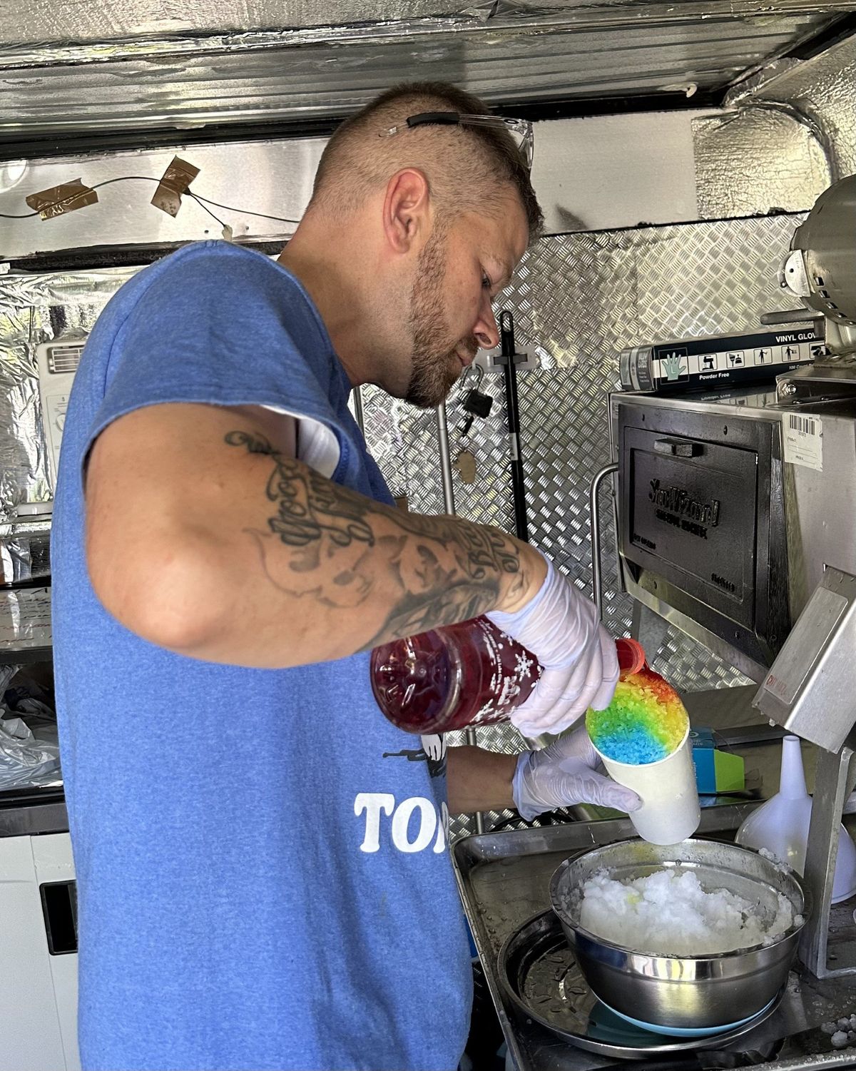 Jarrett Smith puts the finishing touches on a Southern-style rainbow snowball at the Spokane Valley Farmers Market. (Courtesy of Cynthia Reugh)