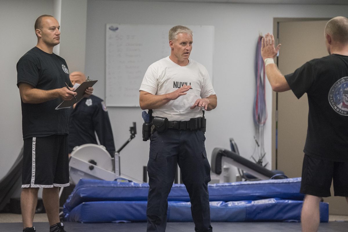 Future law enforcement officer Ryan Nuvill, center, issues commands and approaches a Spokane Police Academy instructor, right, who is pretending to be arrested during final testing for new officers Thursday, June 14, 2017. The hypothetical suspect would put up a variety of resistances which Nuvill would have to counter. After each session, instructors critique the students actions. (Jesse Tinsley / The Spokesman-Review)
