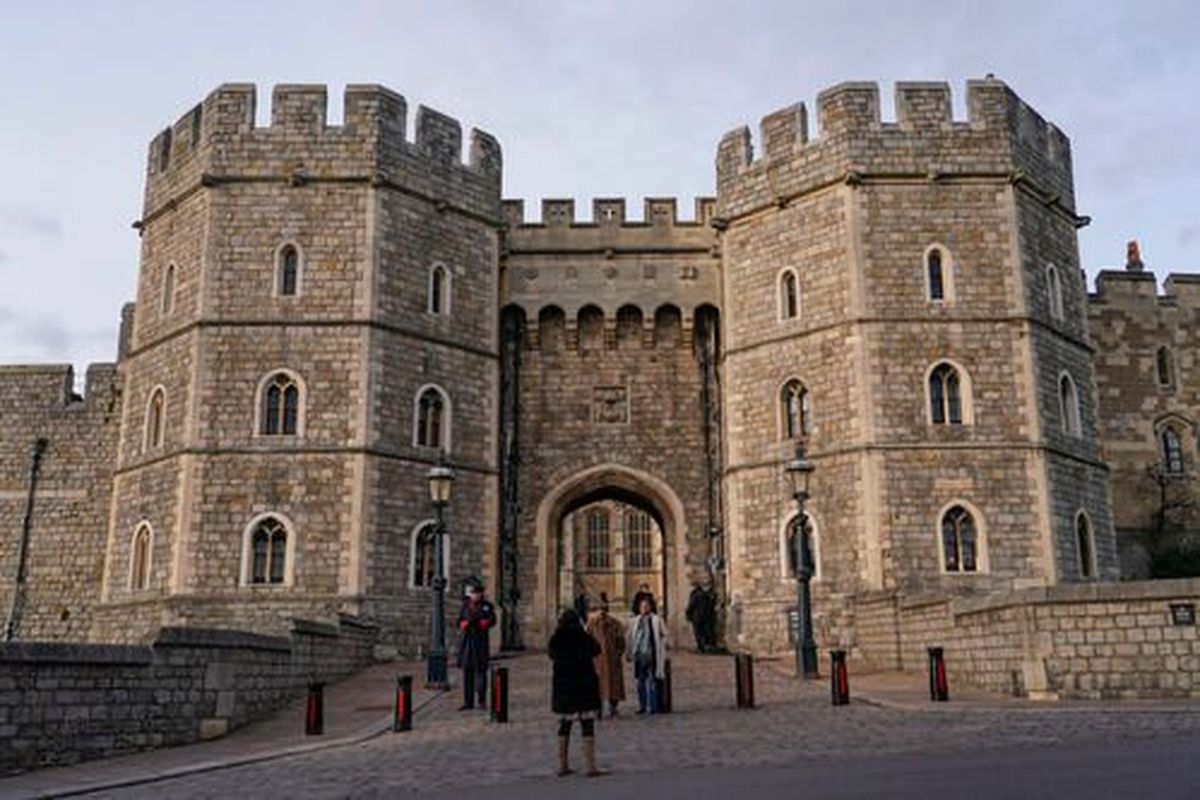 People take photos as police officers patrol the entrance of Windsor Castle, in Windsor, near London, Friday, Feb. 11, 2022. The British Army has launched an investigation after a Spokane priest posed as a friend of the chaplain to gain entry to the barracks of troops who guard Queen Elizabeth II at Windsor Castle.  (Alberto Pezzali)