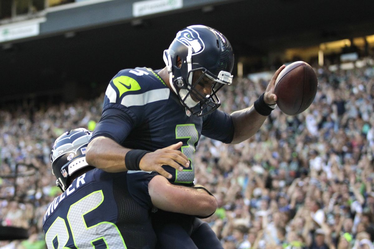 Seahawks tight end Zach Miller gives Russell Wilson a lift after the quarterback ran 7 yards for a first-quarter touchdown. (Associated Press)