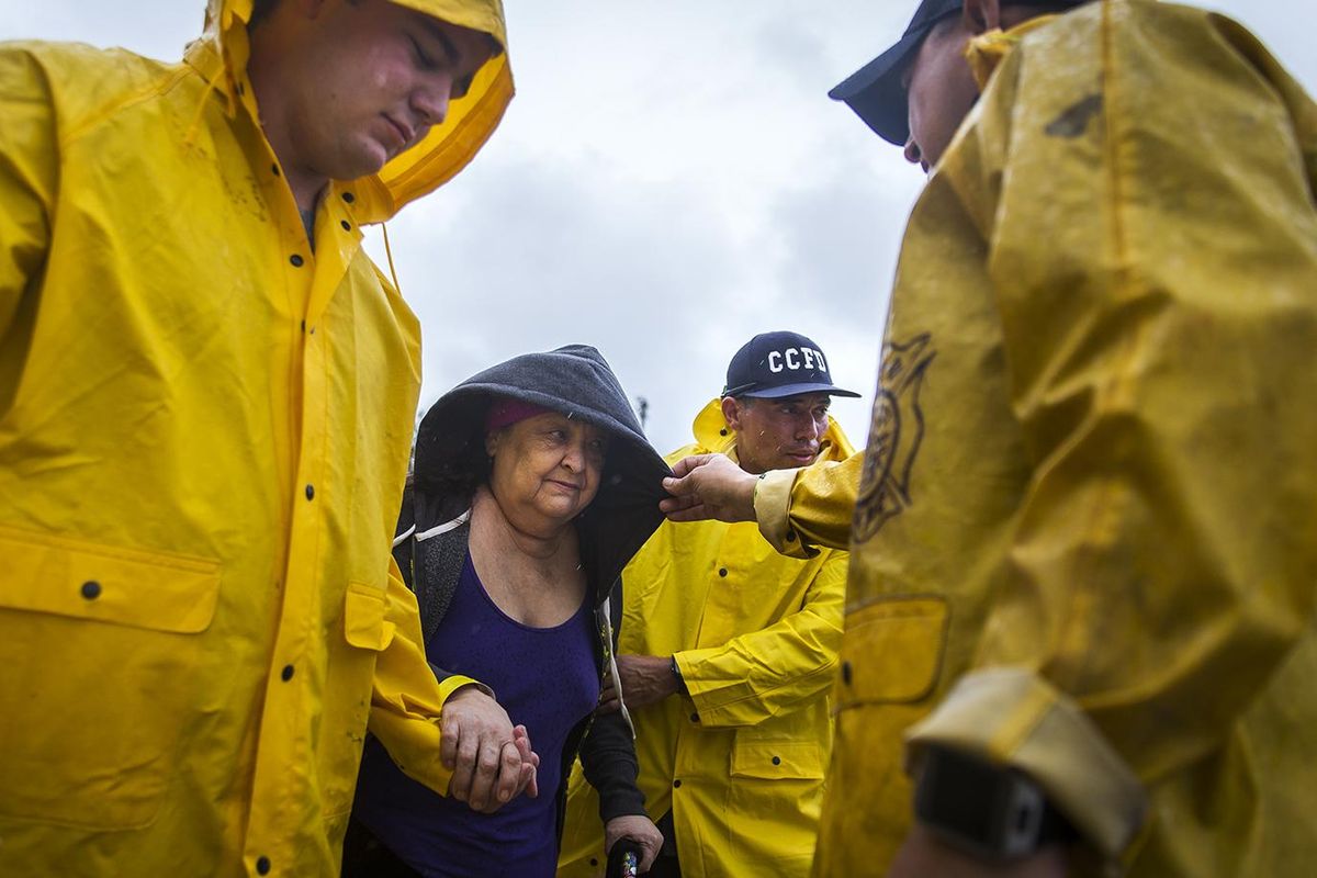 Corpus Christi firefighters help Guadalupe Guerra walk to a bus headed for San Antonio at an evacuation center in Corpus Christi, Texas, on Friday, Aug. 25, 2017. Conditions deteriorated Friday along the Texas Gulf Coast as Hurricane Harvey strengthened and crawled toward the state, with forecasters warning that evacuations and preparations "should be rushed to completion." (Nick Wagner / Associated Press)