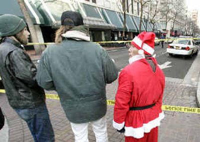 
Sidewalk Santa Remy Villa, right, watches as police investigate the scene of a fatal shooting outside a store Thursday in Portland. 
 (Associated Press / The Spokesman-Review)