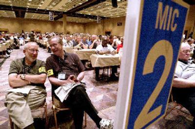 
Steven Haas, left, and Dennis Graf guard a microphone while delegates listen to UAW President Ron Gettelfinger as he addresses delegates. 
 (Associated Press / The Spokesman-Review)