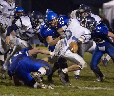 CdA’s Andrew Burgin (65) and Joe Roletto (12) force a fumble in the first half. (BRUCE TWITCHELL photos)