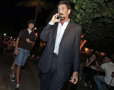 Anti-virus software founder John McAfee talks on his mobile phone as he walks on Ocean Drive in the South Beach area of Miami Beach, Fla., on his way to dinner Wednesday, Dec 12, 2012. McAfee arrived in the U.S. on Wednesday night after being deported from Guatemala, where he had sought refuge to evade police questioning in the killing of a man in neighboring Belize. (Alan Diaz / Associated Press)