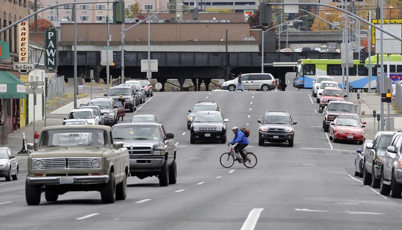 A cyclist crosses Division Street at Main Avenue in Spokane Wednesday. Some say that pedestrian and bicycle traffic going to and from the University District is not safe because they have to cross the busy Division traffic.  (Jesse Tinsley)