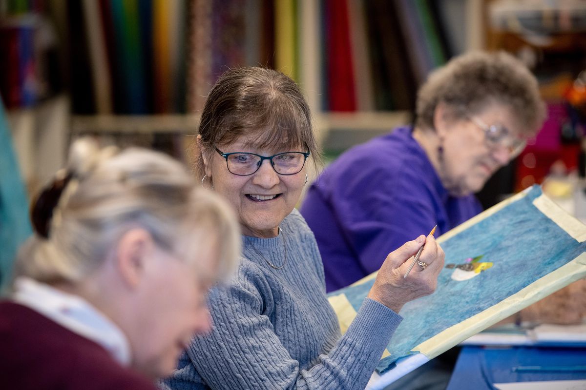 Heidi Carlson, center, has a smile for Carol Ring, left, as they participate with Gerry Walsh, right, in the fabric painting class at Sew Uniquely You in north Spokane on Thursday, Feb. 20, 2020. (Dan Pelle / The Spokesman-Review)