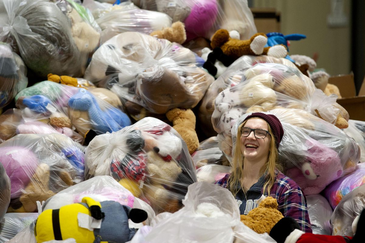 Gonzaga Prep 11th-grader Meg Christopher laughs as she sorts through piles of donated stuffed animals collected from the Teddy Bear Toss at the Christmas Bureau at Spokane County Fair and Expo Center in Spokane Valley on Tuesday. (Kathy Plonka / The Spokesman-Review)