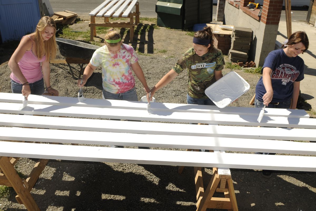 Kerstyn Hendrickson, Natalie Ford, Julia Ford  and Andrea Barenz paint boards for a pergola as part of a home renovation the Construction Academy students are working on at 2004 E. Decatur Ave. 