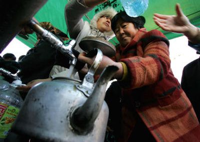 
A resident fills a teapot from a tap outside the Harbin Brewery in Harbin, China, on Friday. The brewery, owned by U.S. beer giant Anheuser-Busch, is providing water from its wells to residents after the city's water system was shut down. 
 (Associated Press / The Spokesman-Review)