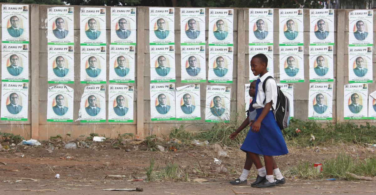 Schoolchildren walk past posters of Zimbabwe