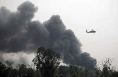 
A helicopter flies Thursday past a column of smoke coming out of Baghdad's heavily fortified Green Zone, which houses the U.S. Embassy and Iraqi government offices. Associated Press photos
 (Associated Press photos / The Spokesman-Review)