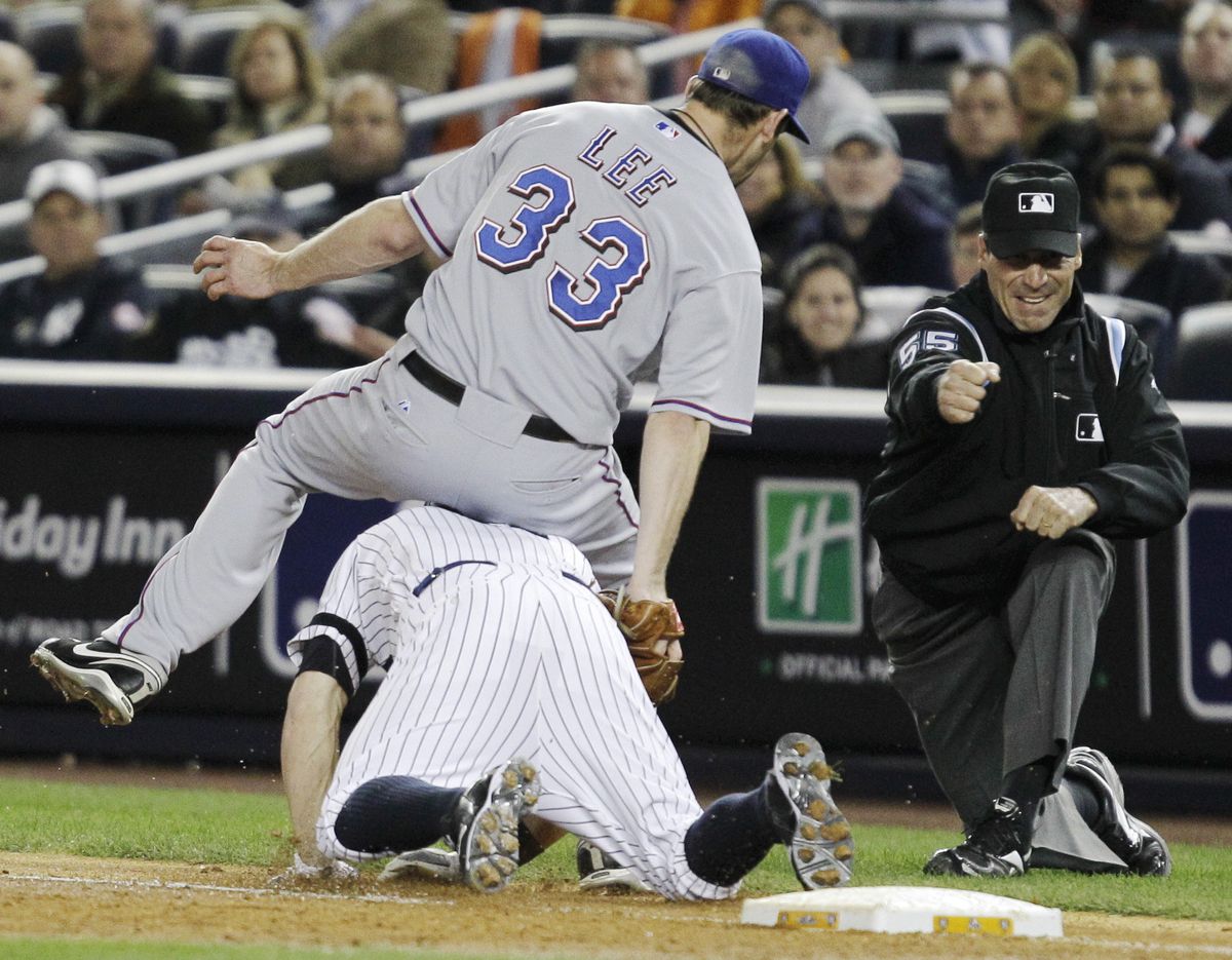 Texas pitcher Cliff Lee falls over New York’s Brett Gardner covering first on an inning-ending out in the third. (Associated Press)