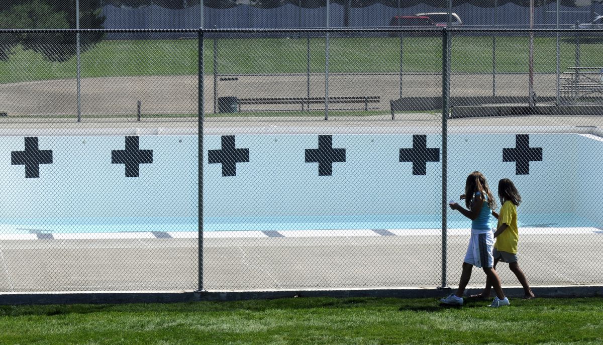 Amanda Parker, left, and Taylor Hoard  walk past the empty  Holmberg pool Wednesday. The pool closed for the season after the arrests of three of its lifeguards.  (Photos by DAN PELLE / The Spokesman-Review)