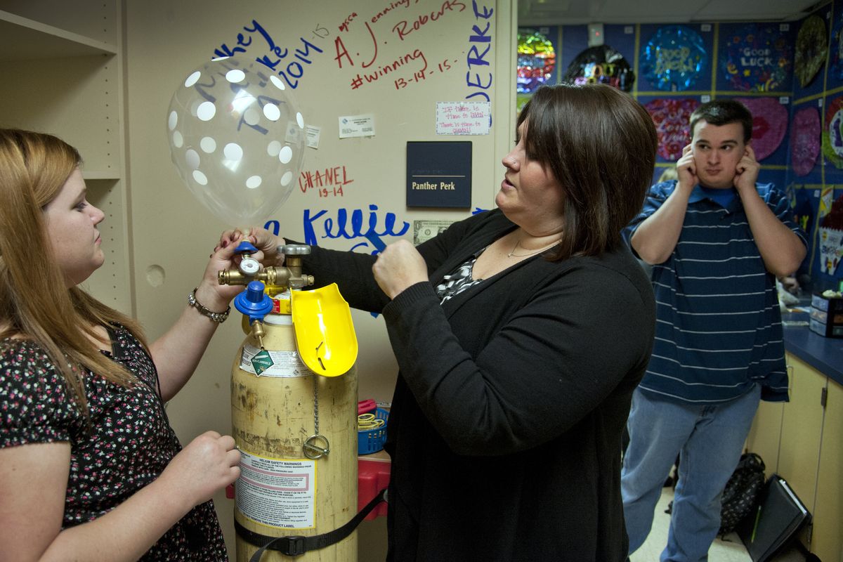 Mead High School Developmental Learning Center teacher Beth Dolezal, center, gives balloon inflation instructions to her students, Katy Schuler, left, and Bryce Lewellen, right, before opening the Big Cat Balloon Shop for mid-morning business Tuesday in Mead. (PHOTOS BY DAN PELLE)