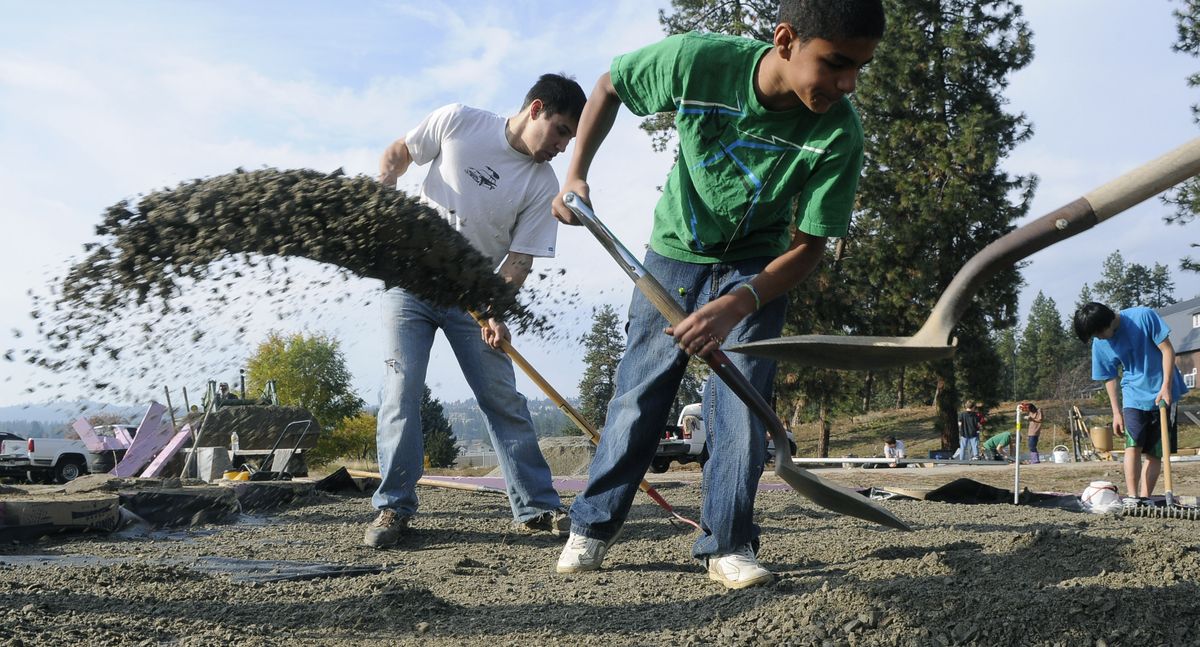 Russell Hyslop, left, and Hutton Settlement resident Milik Mackin help spread gravel around the floor for  a new greenhouse on Saturday. Sean Lyonnais has adopted construction of the greenhouse as his Eagle Scout project.  (PHOTOS BY DAN PELLE)