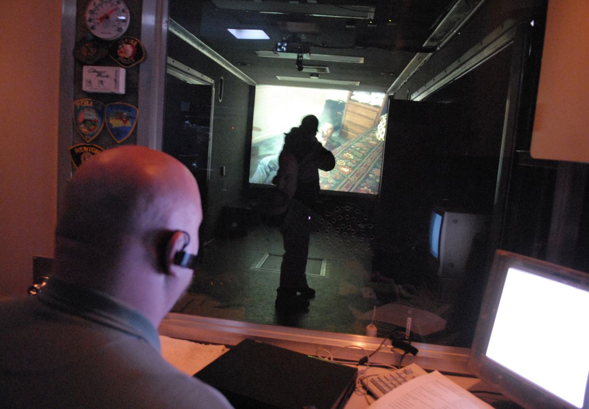 Liberty Lake police Officer Brad Deines (silhouetted in front of screen) goes through a building entry scenario as part of his training.  (J. BART RAYNIAK / The Spokesman-Review)