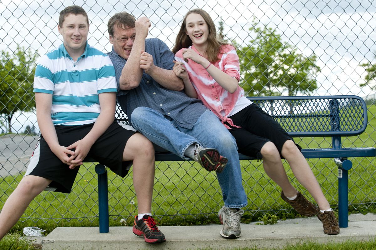 Gary Crooks and his two kids, Carly and Calvin, sit on a bench named for the children’s mother, Laura Crooks, at Moran Prairie Elementary. (Tyler Tjomsland)