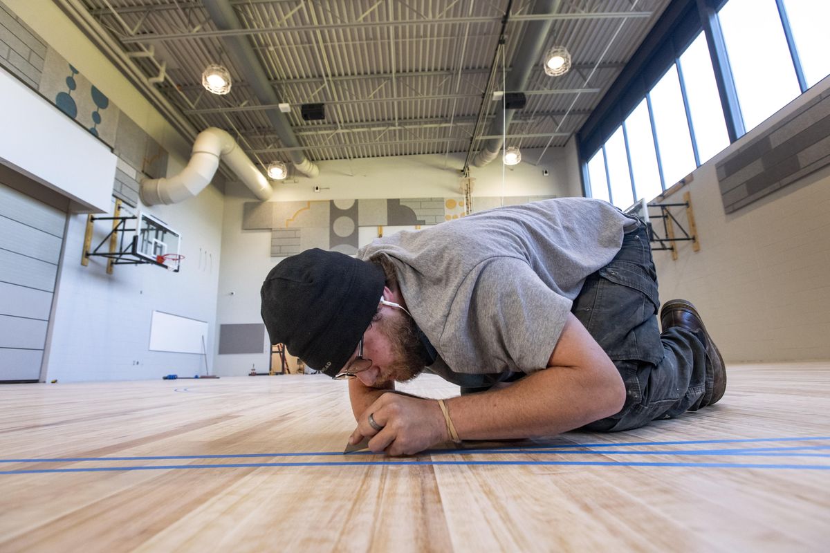 Brandon Thomas with Northwest Hardwoods prepares an outline for the basketball three-point line that will be painted on the court of the new Franklin Elementary School gym that is part of the renovation and new construction at the school. (Colin Mulvany / The Spokesman-Review)