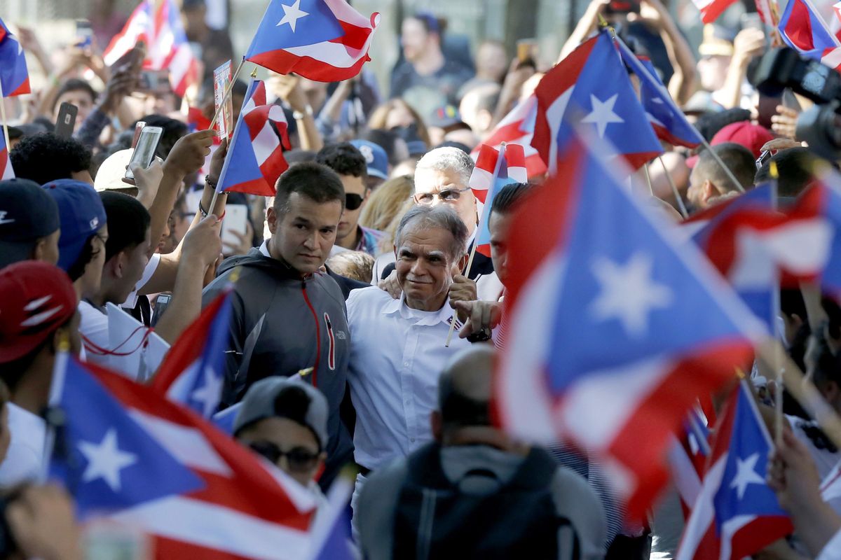 In this May 18 photo, Puerto Rican nationalist Oscar Lopez Rivera, center, arrives for a gathering in his honor in Chicago’s Humboldt Park neighborhood. New York City’s annual Puerto Rican Day parade will take place under a cloud of controversy this year because of a decision by organizers to honor OscarLopez Rivera, who spent decades in prison because of his involvement with the terrorist group FALN. (Charles Rex Arbogast / Associated Press)