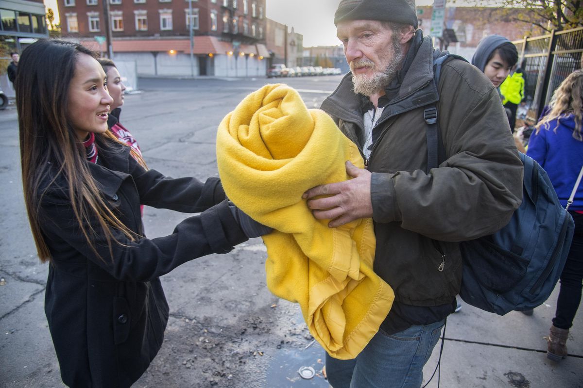 Rogers High School sophomore Dana Tran offers a yellow blanket to Ralph Crowley on Monday, Nov. 6, 2017, at the House of Charity in Spokane. Students collected goods to pass out to the homeless. (Dan Pelle / The Spokesman-Review)