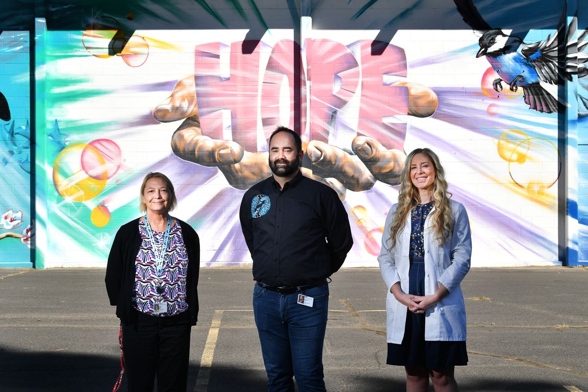 Excelsior Wellness staff members Sue Bell, medical care coordinator; Andrew Hill, CEO; and Miranda Hennes, psychiatric and mental health nurse practitioner, stand for a photo in front of a mural painted by local artist Daniel Lopez in the Excelsior Holistic Schools building Sept. 23 in Spokane.  (Tyler Tjomsland/The Spokesman-Review)