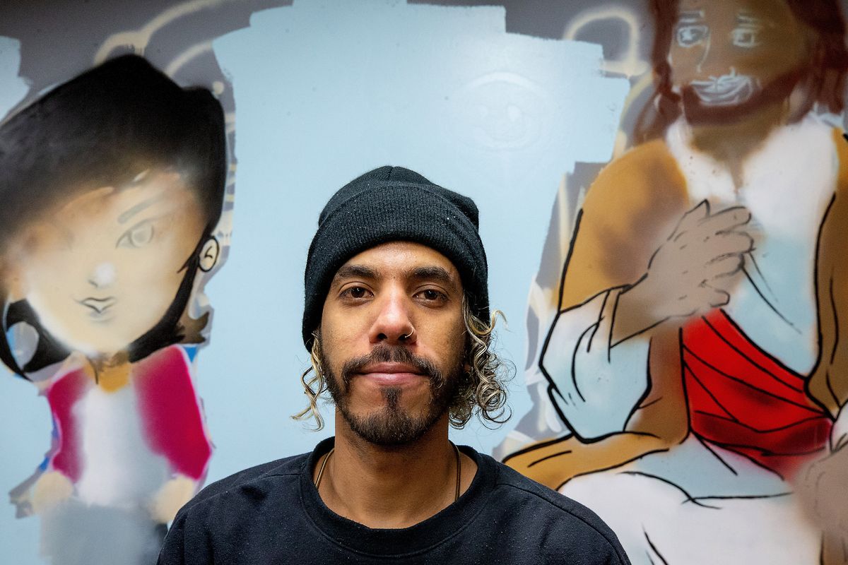 Dario Rodriguez poses in front of a partially finished mural he is painting in “The Hook” youth center at Lighthouse Ministries in Wenatchee on April 18.  (Don Seabrook/Wenatchee World)