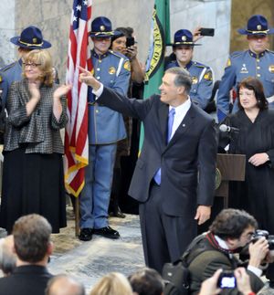 OLYMPIA -- Gov. Jay Inslee waves to the crowd after being sworn in by Chief Justice Barbara Madsen, as his wife Trudi Inslee (back, left) claps.  (Jim Camden)