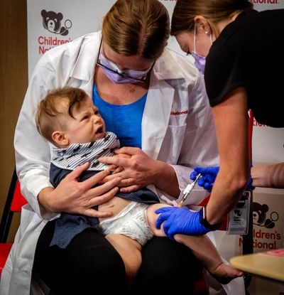Physician Sarah Schaffer Deroo holds her 7-month-old son Hewitt as he receives a coronavirus vaccine in Washington, D.C.  (Bill O'Leary/The Washington Post)