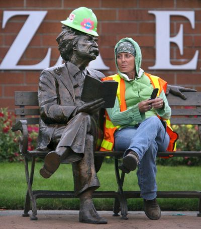 ORG XMIT: WAOLY101 Construction flagger Patty Nevers of Tacoma, Wash., sits next to a statue of Mark Twain as she waits for the start of a paving project along Capitol Boulevard in Tumwater, Wash., on Friday, Aug. 21, 2009. (AP Photo/The Olympian, Tony Overman) (Tony Overman / The Spokesman-Review)