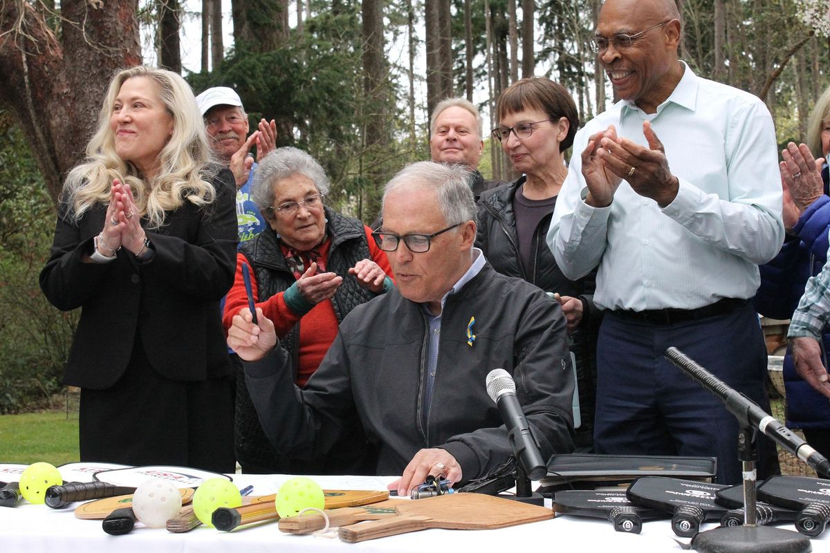 Surrounded by pickleball advocates, Gov. Jay Inslee signs a bill designating pickleball as the official state sport.  (Albert James)