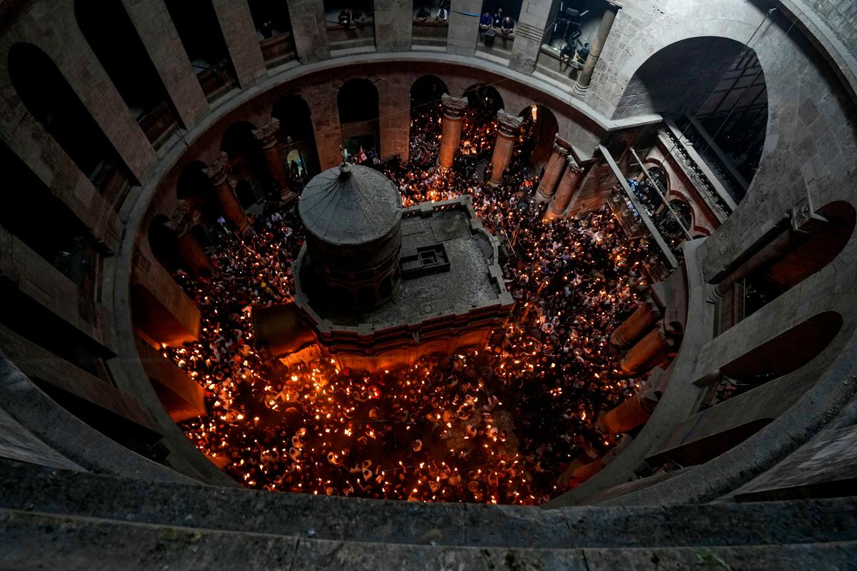 Christian pilgrims hold candles as they gather during the ceremony of the Holy Fire at Church of the Holy Sepulchre, where many Christians believe Jesus was crucified, buried and rose from the dead, in the Old City of Jerusalem dead, Saturday, April 23, 2022.  (Tsafrir Abayov)