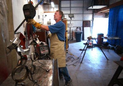 
Dave Henke hangs up his welder's mask after putting the paws on some of his metal dog statues in his garage in Greenacres. 
 (Liz Kishimoto / The Spokesman-Review)