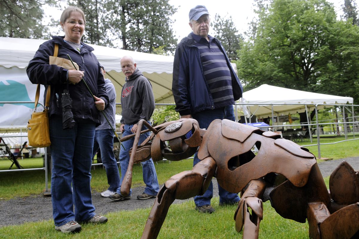 Doreen, left, and Greg  Preuss, of Mead,  stop in their tracks while viewing “G.I. Ant,” a metal sculpture by Bill and Karma Simmons, of Spokane. The Simmonses invested more than 80 hours  in the project, Bill Simmons said. The Preusses were visiting ArtFest  in Spokane’s Coeur d’Alene Park on Friday. (Dan Pelle)