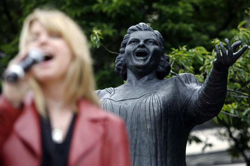 Philadelphia Flyers' national anthem vocalist Lauren Hart sings next to a statue of Kate Smith during a ceremony where a design of a postage stamp honoring Smith was presented, in Philadelphia, Wednesday, May 19, 2010. Smith was best known for performing composer Irving Berlin's