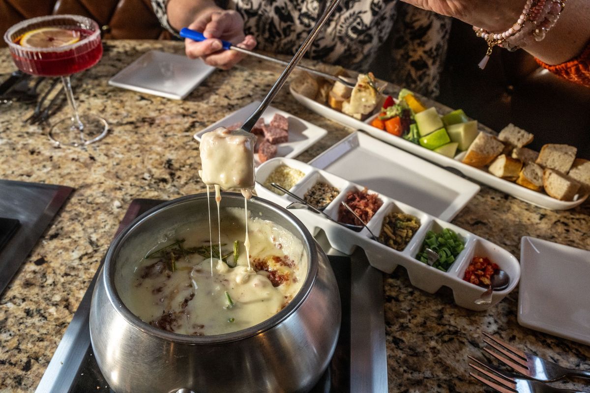 The Melting Pot chain is celebrating its 50th anniversary. In celebration, the chain debuted the Grand Reserve Cheese Fondue, a limited-edition alpine blend of Grand Cru, sweet Fontana, Swiss melted with sherry, shallots, garlic and candied bacon topped with a one-year aged cheddar and golden chives. Here it is served with artisan breads and seasonal fruit and veggies.  (Colin Mulvany/The Spokesman-Review)