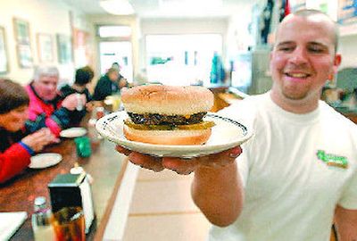 
Eli Weston, cooking in place of co-owner Steve Hudson, holds up a hamburger before serving a customer Tuesday at Hudson's Hamburgers.
 (Jesse Tinsley / The Spokesman-Review)