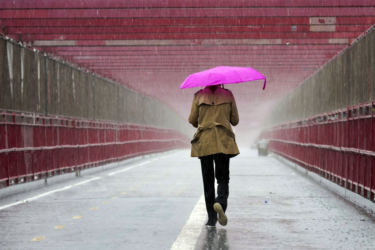 A pedestrian walks during a heavy downpour of rain over the Williamsburg bridge, Tuesday, Oct. 26, 2021, in New York. A flash flood watch is in effect as a nor