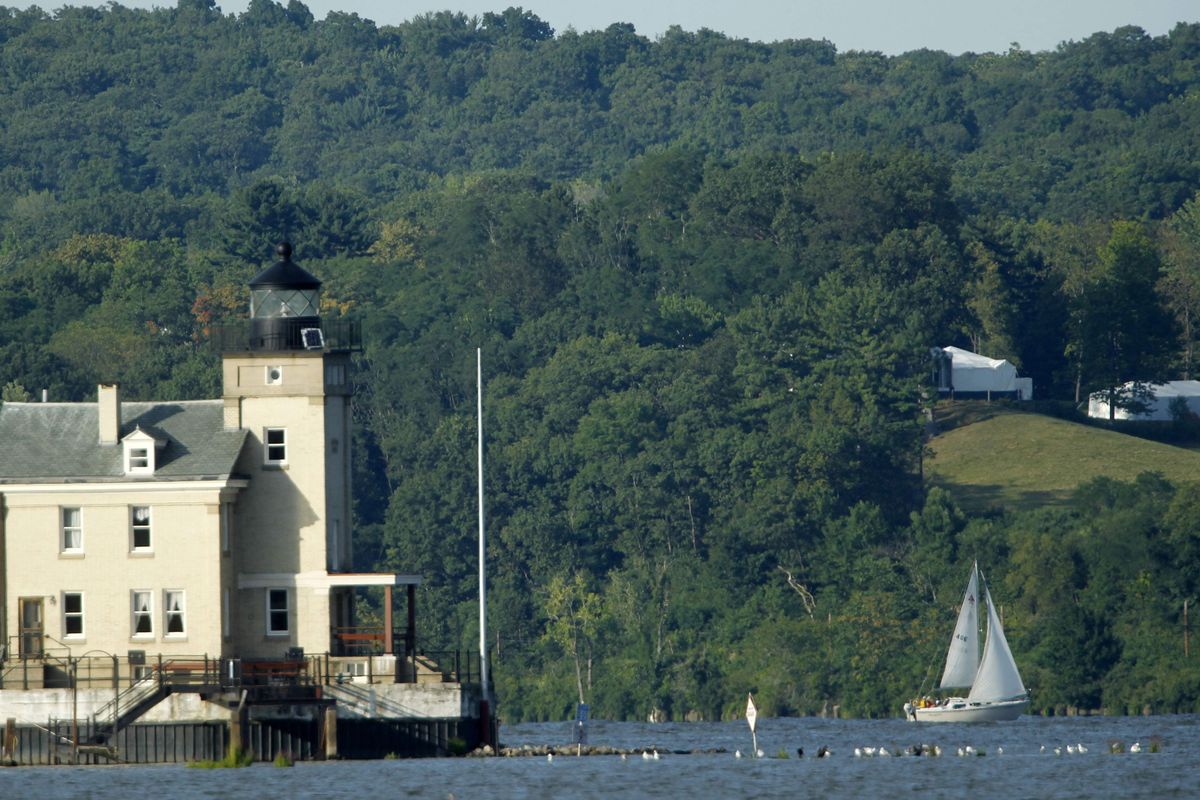 Tents are seen at Astor Courts in Rhinebeck, N.Y., right, as a sail boat moves along the Hudson River past the Rondout Lighthouse in Port Ewen, N.Y., on Saturday, July 31, 2010.  The wedding of Chelsea Clinton and Marc Mezvinsky was taking place at Astor Courts. (Mike Groll / Associated Press)