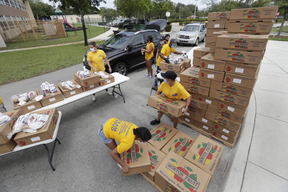 Volunteers load groceries into cars during a food distribution event, Tuesday, July 21, 2020, at St. Monica