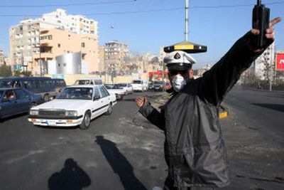 
A police officer in Beirut, Lebanon, directs traffic Wednesday as he wears a mask to avoid pollution after Tuesday's confrontations, in which Hezbollah-led protesters burned tires and blocked roads. 
 (Associated Press / The Spokesman-Review)