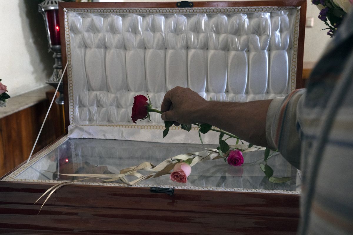 A friend places a rose on the open-faced casket that contains the remains of slain journalist Armando Linares in Zitacuaro, in the state of Michoacan, Mexico, Wednesday, March 16, 2022. Linares was shot to death at a home in the town of Zitacuaro on Tuesday, the eighth Mexican journalist murdered so far this year.  (Marco Ugarte)