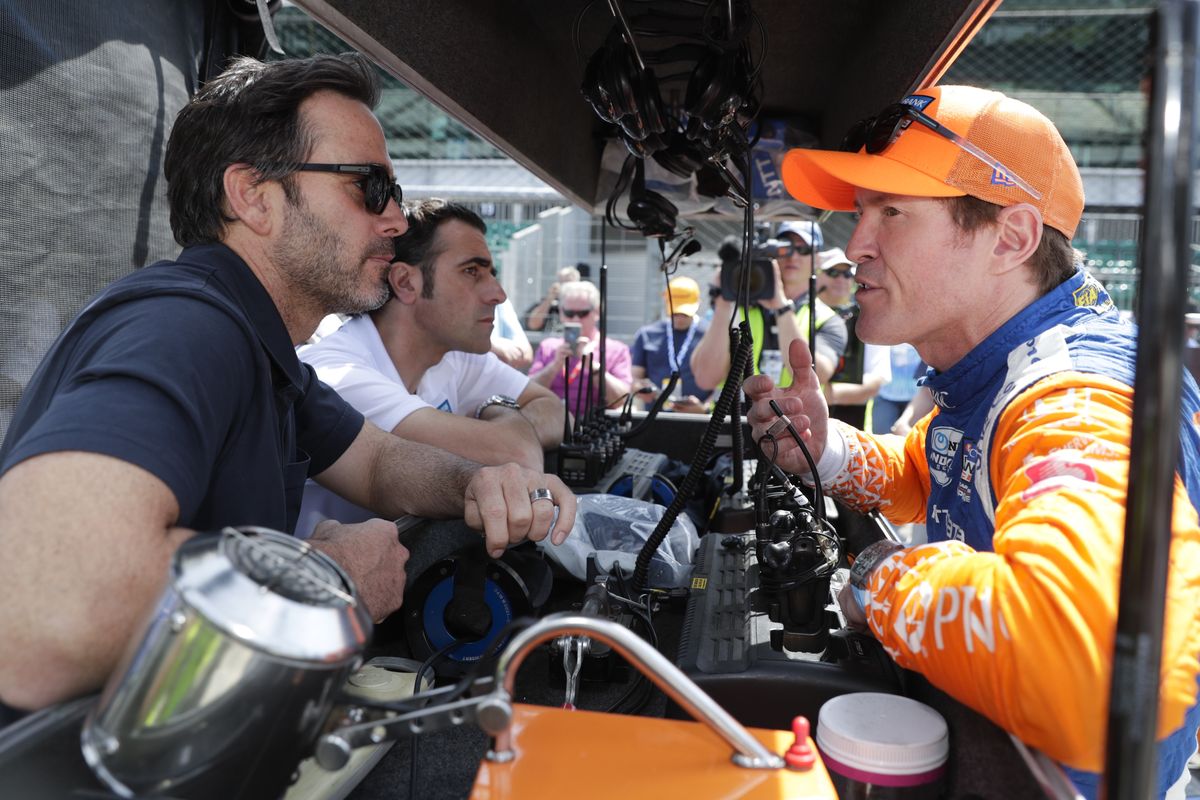 NASCAR driver Jimmie Johnson, left, and Indycar driver Scott Dixon, right, talk during practice for the Indianapolis 500 IndyCar auto race at Indianapolis Motor Speedway in Indianapolis, in this May 2019 photo. Three-time Indy 500 champion Dario Franchitti sits, second from left. The IndyCar season begins with three new drivers, including seven-time NASCAR champion Jimmie Johnson.  (Associated Press)