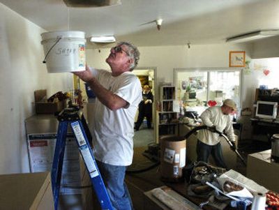 
Spike Cunningham catches water from a hole in the ceiling after a sprinkler pipe broke on the second floor of  the Center Pointe building on  Saturday.  E. J. McGrane of Summit Restoration vacuums some water off  the floor. 
 (Dan Pelle / The Spokesman-Review)