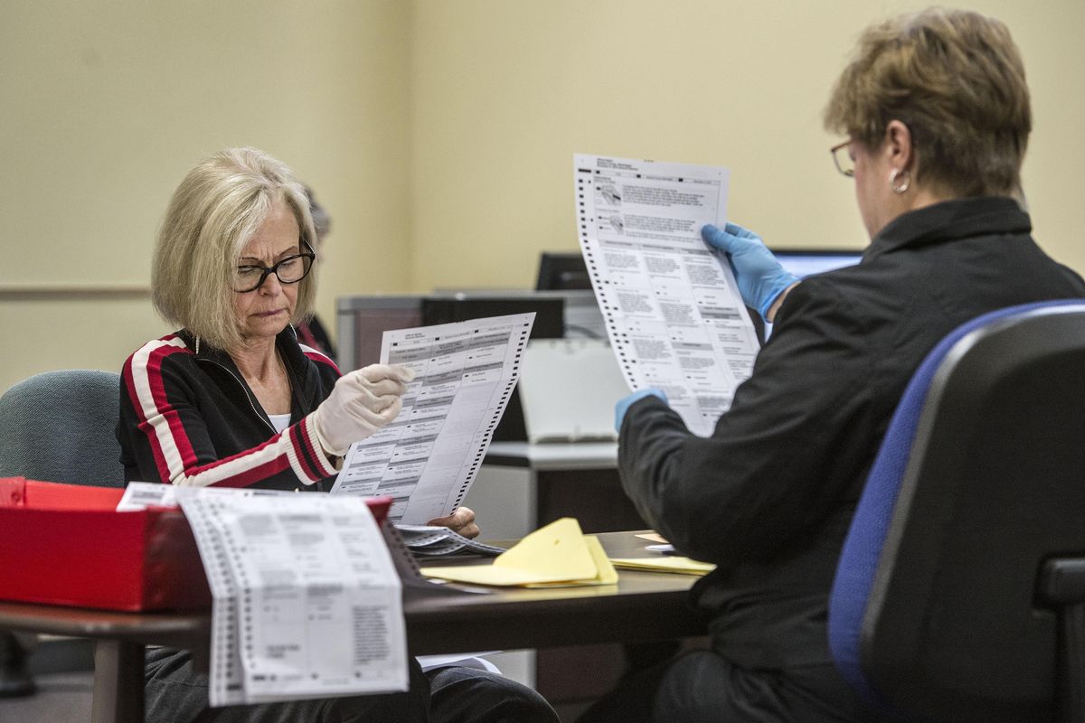 Spokane County election workers Pat Curiale, left, and Sue Harvey inspect ballots for machine readability, Oct. 25, 2016, at the election center. (Dan Pelle / The Spokesman-Review)
