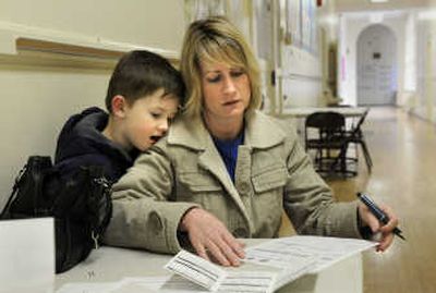 
Parker Mason vies for the attention of his mother, Stephanie Mason, as she fills out kindergarten registration forms, on Tuesday in a hallway at Hutton Elementary School.  Spokane Public Schools has a new marketing campaign to attract more families. After losing more than 600 students last year, they plan to give each new student a book bag filled with goodies.  
 (Dan Pelle / The Spokesman-Review)