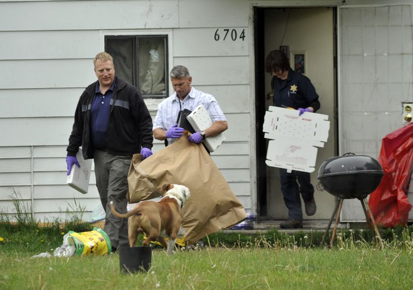 Detective Michael Drapeau, front, and investigators with the Spokane County Sheriff’s Office remove evidence from a house at 6704 E. Third Ave., where Shane Smith, 38, was arrested Tuesday afternoon in connection with the homicide of Warren Flinn. (Colin Mulvany)